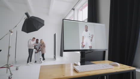 Monitor-with-an-advertising-cover-of-the-picture-On-the-background-a-photographer-a-football-player-a-model-and-a-director-look-at-photos-from-a-photo-shoot-for-the-cover-on-a-camera